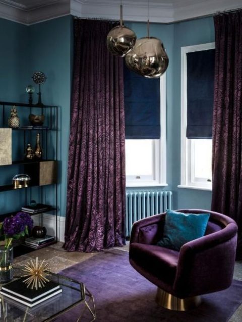 a stone blue living room with a purple rug and an aubergine chair plus matching printed curtains