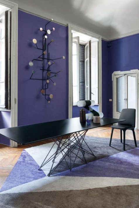 a bold very peri dining room with a black dining table with a catchy base, a black chair and a catchy shelf on the wall