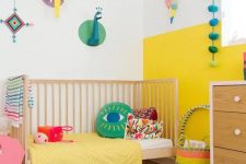 40 a modern colorful kid’s room with a color block yellow and white wall, bright bedding and a rug, cardboard taxidermy and accessories