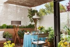 43 a small and bright deck with simple outdoor furniture, a roof over the space, bright blooms and plants is a cool space
