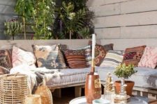44 an inviting deck with a corner pallet bench and printed pillows, round tables, candle lanterns and potted greenery and climbing plants