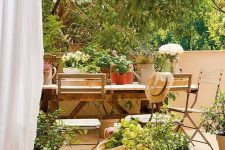 45 a beautiful Mediterranean terrace with a simple wooden dining table, potted plants and blooms, a jute pouf is very welcoming