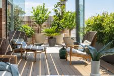 49 a chic and stylish rooftop terrace with a slight planked roof, potted plants and trees, rattan and woven furniture and a low coffee table