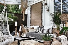 50 a boho outdoor living room with a glass roof, a large sofa, jute rugs and poufs, woven chairs and printed pillows