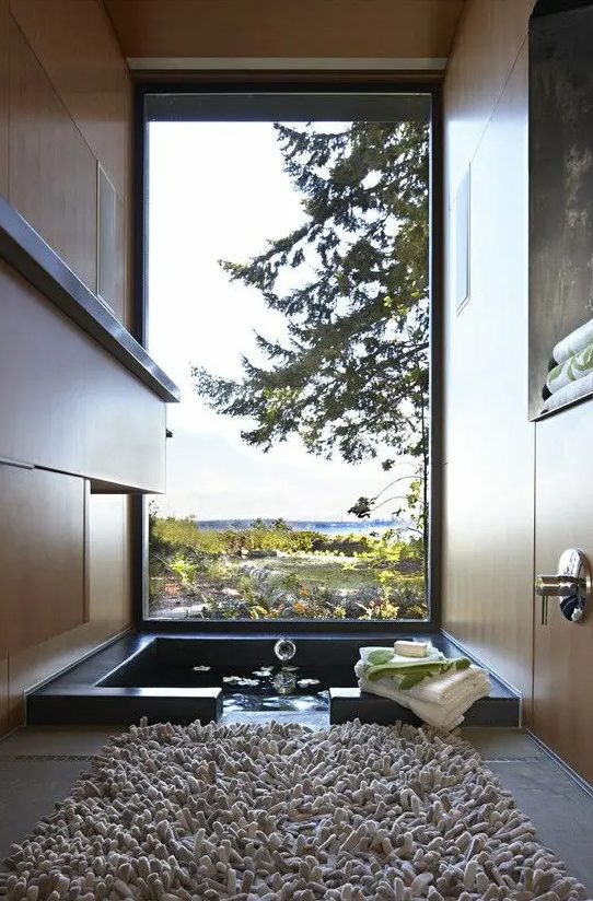 a gorgeous bathroom with a view, with an ofuro tub and a fluffy rug is a real relaxation oasis