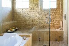 53 a beautiful warm-colored bathroom with a large shower space with glass doors and a bathtub clad with tiles