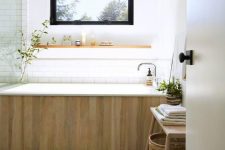 55 a spa-like bathroom in neutrals, with a glass-enclosed shower, a bathtub clad with wood and a wooden bench with a basket