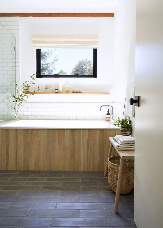 a spa-like bathroom in neutrals, with a glass-enclosed shower, a bathtub clad with wood and a wooden bench with a basket