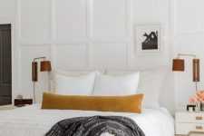 58 a sophisticated neutral bedroom with a creamy upholstered bed, an upholstered bench, leather sconces, white refined nightstands and paneled walls