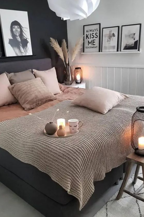 a stylish bedroom with a black accent wall, white paneling, a black bed with blush bedding and pretty artworks is very elegant