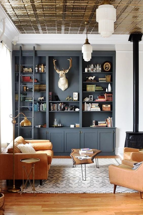 a beautiful living room with a slate grey bookcase, a vintage black hearth, amber leather furniture, a living edge coffee table and pendant lamps