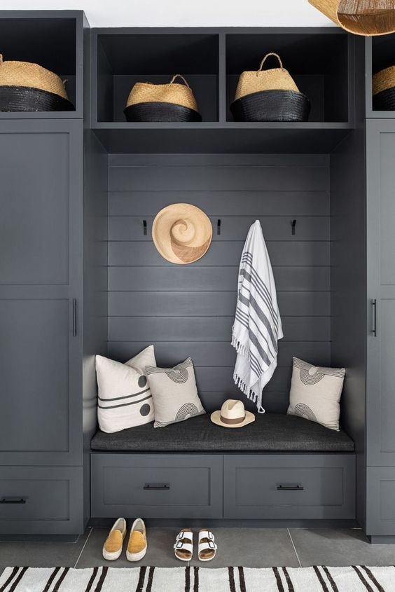 a beautiful slate grey mudroom unit with baskets, racks, drawers and cabinets for storage, striped textiles
