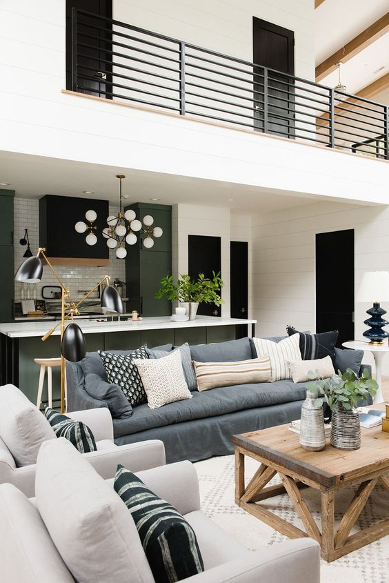 a black and white space with green kitchen cabinets, light-stained furniture items and a slate grey sofa