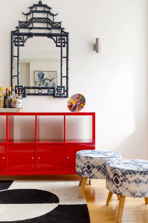 a bold space with a graphic rug, printed stools, a coquelicot credenza and an Asian-inspired mirror on the wall