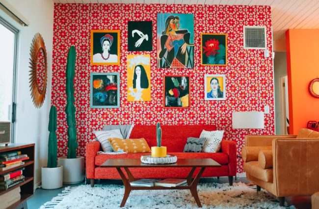 a bright mid-century modern living room with a coquelicot printed wallpaper wall, a matching plain sofa, a bright gallery wall and elegant modern furniture