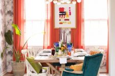 a colorful dining space with printed wallpaper, a wooden table, mismatching chairs, coquelicot curtains and matching touches on the table
