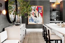 a contasting dining room with black grasscloth wallpaper, creamy furniture, built-in shelves and a mirror in a black frame