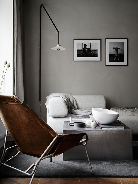 a contemporary exquisite space with light grey walls, a white sofa, a slate grey coffee table and a rug, a brown leather chair