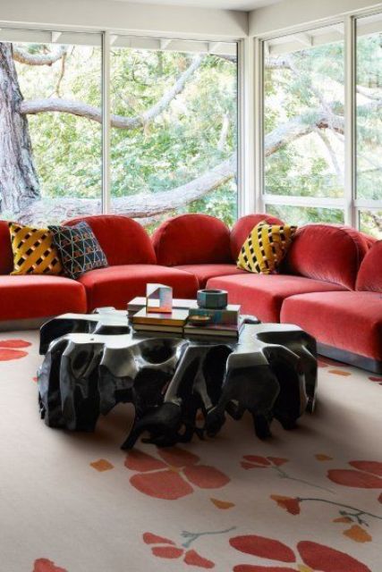 a fantastic glazed space with a large coquelicot sectional sofa, a catchy table of wood, a coquelicot printed rug and bold pillows