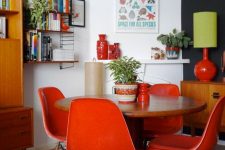 a mid-century modern dining space with a stained table, coquelicot chairs, potted plants and blooms and some art