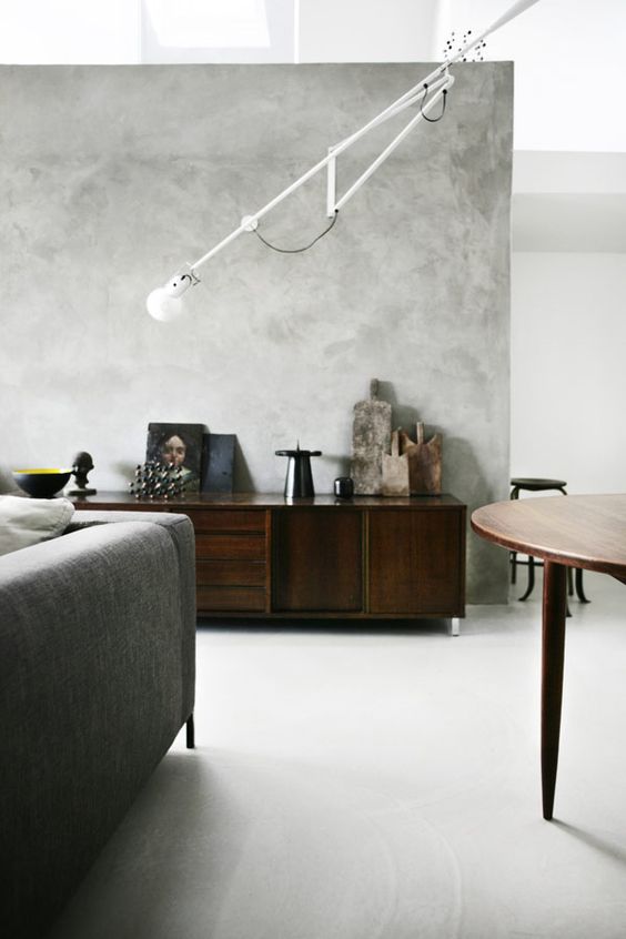 a modern living room with grey limewashed walls, a grey sofa, dark-stained furniture and a sconce
