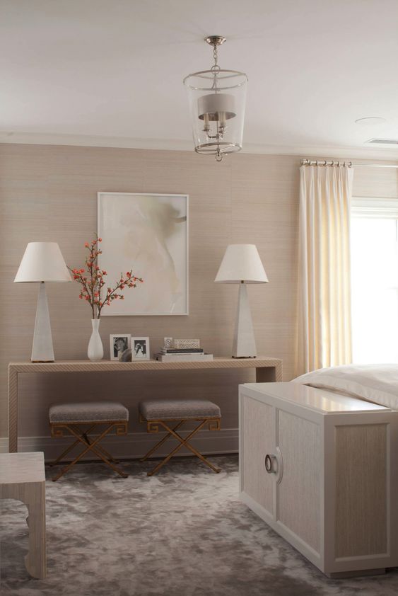 a modern neutral bedroom with tan grasscloth wallpaper, elegant neutral furniture, a crushed velvet rug and a chic pendant lamp