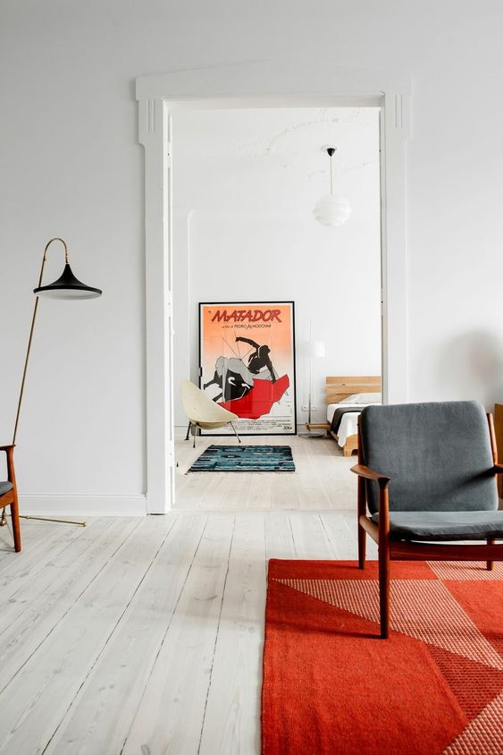 a neutral living room with grey chairs, a floor lamp and a bold coquelicot rug with prints that makes an accent