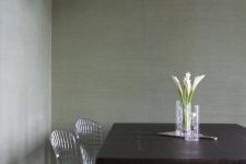 a simple dining space with green grasscloth wallpaper, a dark-stained table, wire chairs and a yarn ball lamp