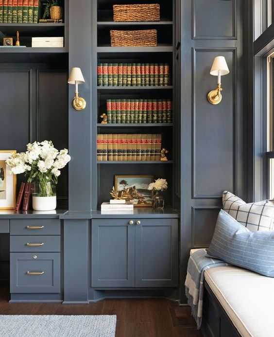 a slate grey bookcase and storage units with brass touches and a matching built-in windowsill daybed are elegant and timeless