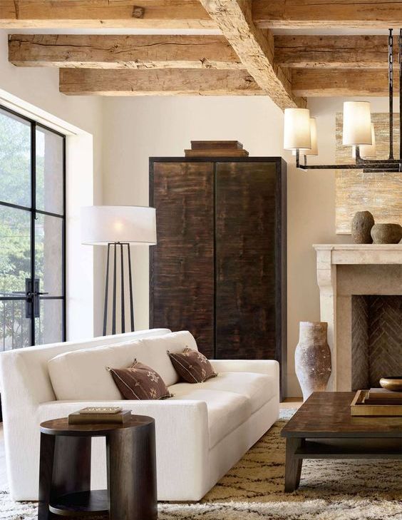 a stylish contemporary living room with rough wooden beams, a white sofa, a dark stained wardrobe, a low coffee table and a stool