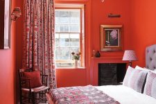 a super bold coquelicot bedroom with vintage stained furniture, printed bedding and curtains and wall sconces is amazingly energetic