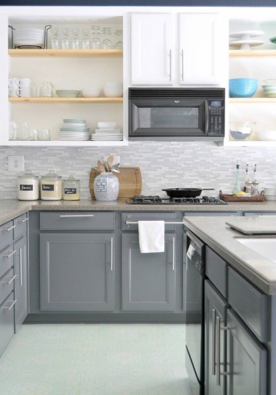 a two-tone kitchen with white upper cabinets and grey lower ones, with stone countertops, open shelves and neutral handles