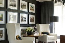 a vintage living room with black grasscloth wallpaper, creamy chairs and a chic gallery wall and a vintage chandelier