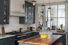 a welcoming kitchen with slate grey shaker style cabinets, a white subway tile backsplash, a wooden stool and pendant lamps