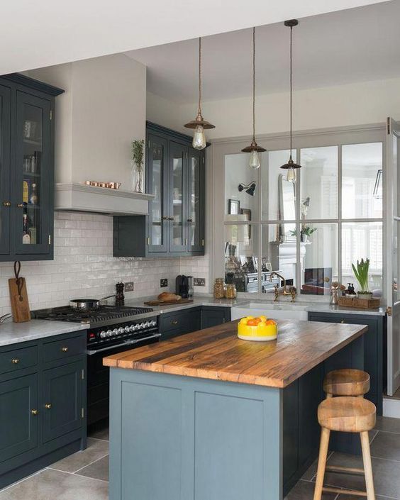 a welcoming kitchen with slate grey shaker style cabinets, a white subway tile backsplash, a wooden stool and pendant lamps