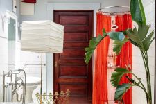 a whimsical bathroom with a hex tile floor, a clawfoot tub, a shower space with coquelicot curtains, a floor lamp and a gold chair
