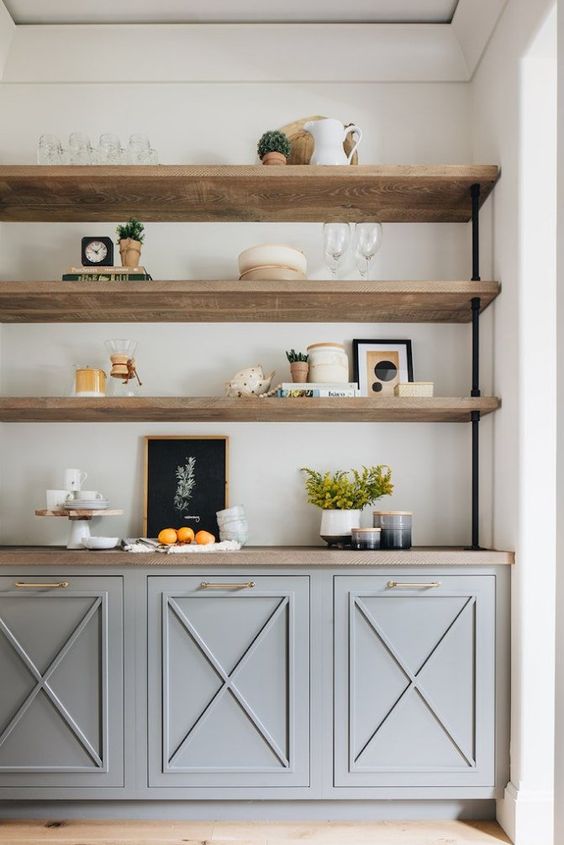 an elegant storage unit with grey paneled cabinets, rough wood shelves and various objects on display
