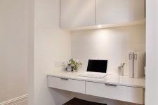 08 a sleek white working space with a large sleek cabient for storage, a built-in desk, a dark stool and some built-in lights