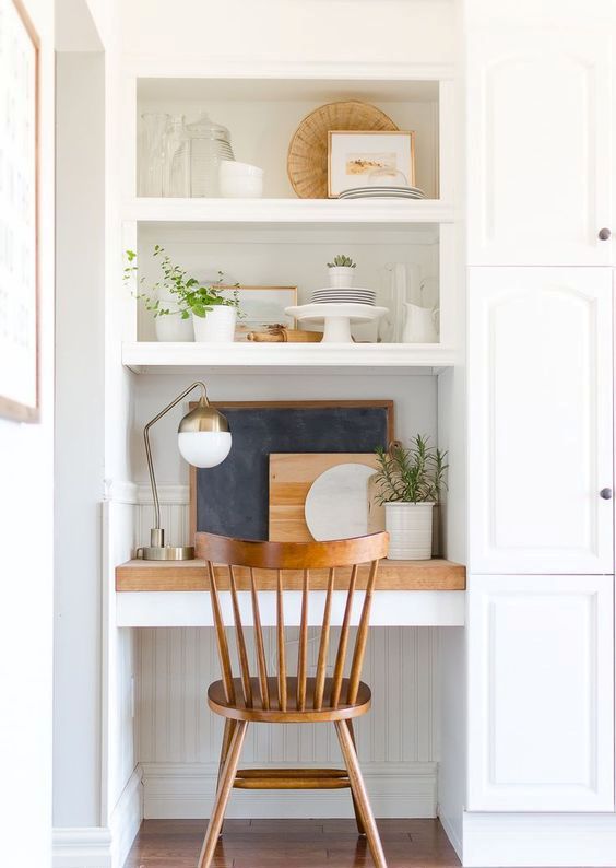 a small nook with a built-in working space - a desk, a couple of shelves, potted greeneyr and some cutting boards can be located in the kitchen