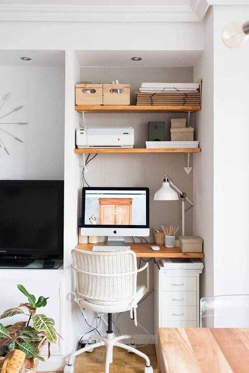 a tiny awkward nook space taken by a built-in working space - a desk, some shelves and a white office chair plus a white table lamp