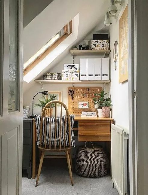 a small and cozy attic nook with a desk, a file cabinet, some shelves for storage and lots of plants is a great work spot
