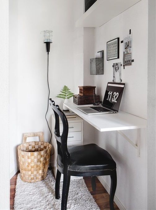 a small and lovely nook with a floating desk and a shelf, a black leather chair, a basket and a tiny file cabinet under the desk
