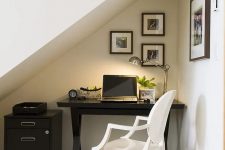 34 a small attic nook with a trestle black desk and a file cabinet, a white chair, a small gallery wall and a table lamp