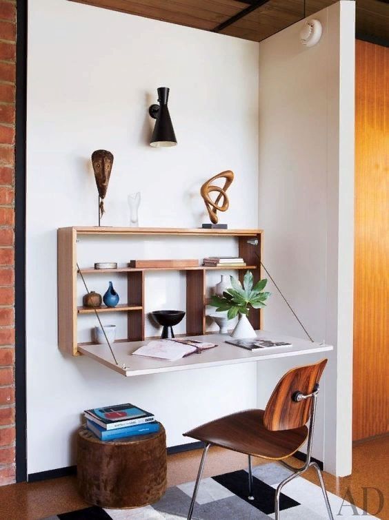 a small nook taken by a Murphy desk, a plywood chair, potted plants and a pouf for a lovely modern space