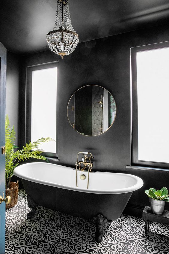 a beautiful black bathroom with sleek walls, a crystal chandelier, a lovely printed tile floor and a black clawfoot bathtub