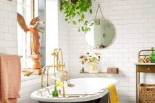 a black and white bathroom with a chic black clawfoot bathtub and bright touches – yellow and pink towels, a vintage chair, statues and potted plants