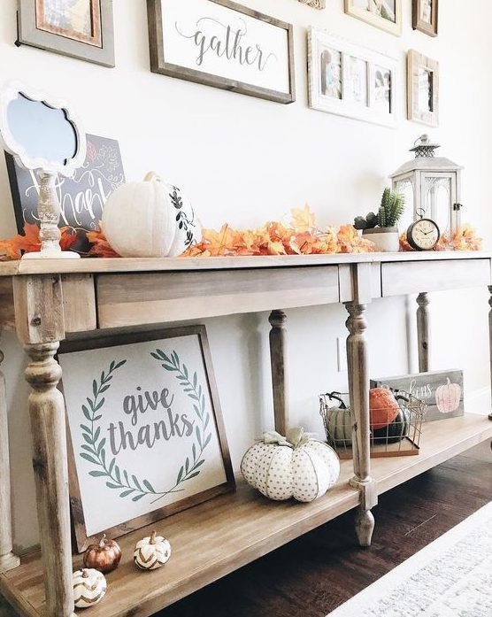 a bright fall or Thanksgiving console table with colorful fall leaves, fabric or plastic pumpkins and a lantern