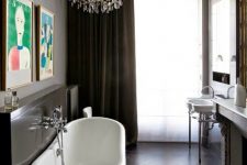 a gorgeous French bathroom with a vintage feel, with a free-standing sink, a fireplace, a vintage black clawfoot bathtub and a crystal chandelier