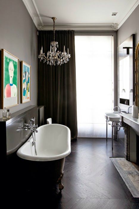 a gorgeous French bathroom with a vintage feel, with a free-standing sink, a fireplace, a vintage black clawfoot bathtub and a crystal chandelier