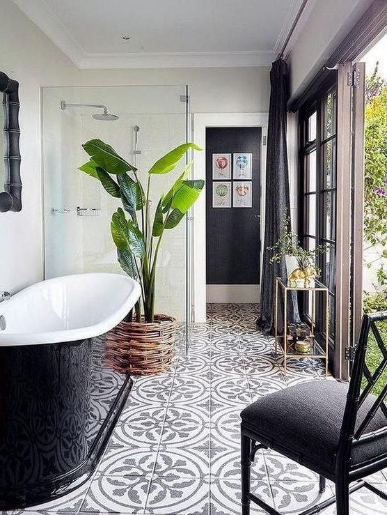 a lovely modern bathroom with a door to the garden, a shower, a black sleek bathtub, a black chair and cool tiles on the floor